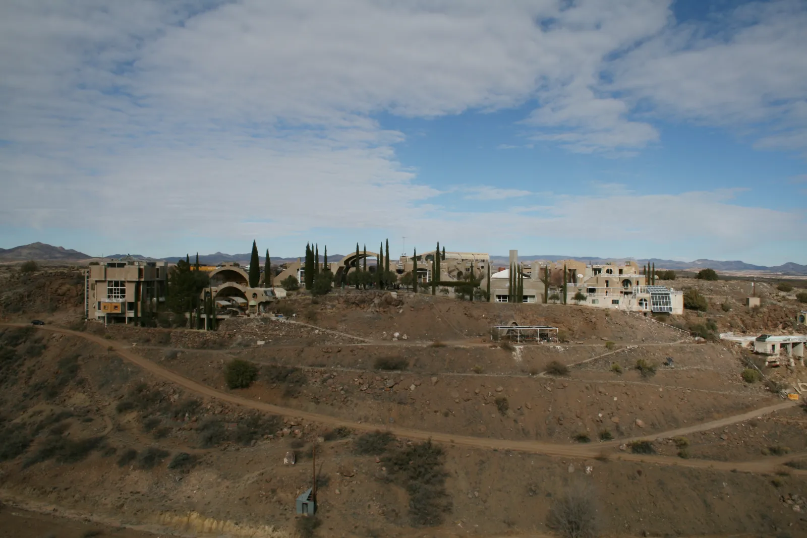 Arcosanti structures viewed from below — layered concrete forms rising from the desert